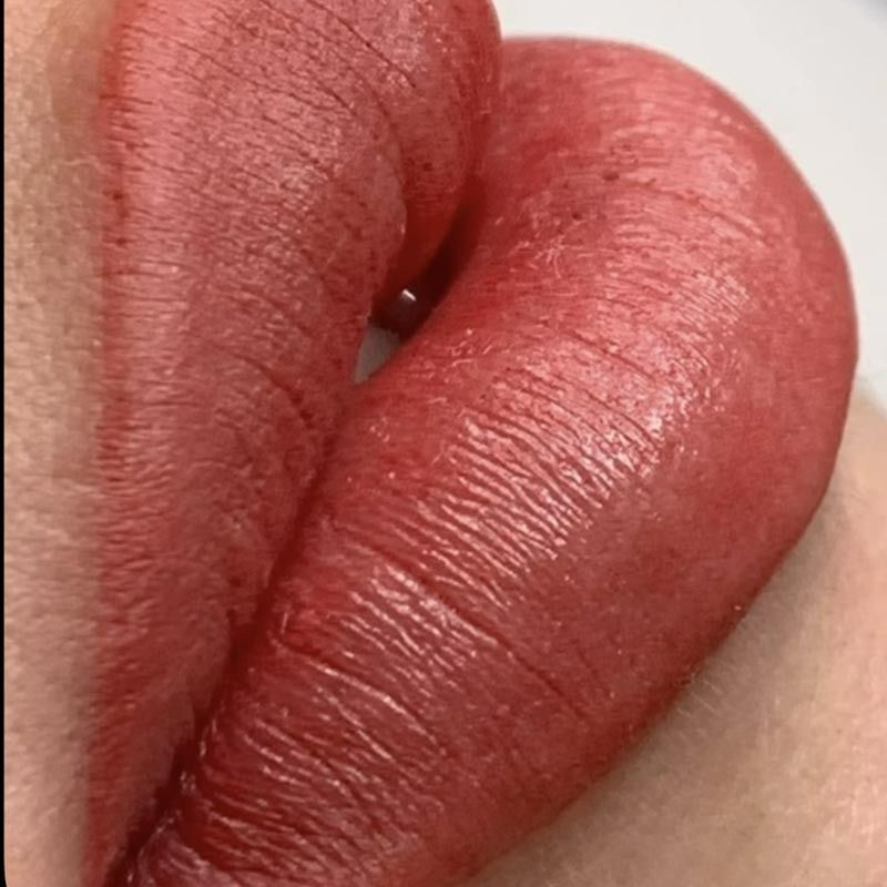 Un primer plano de los labios de una mujer con lápiz labial rojo.