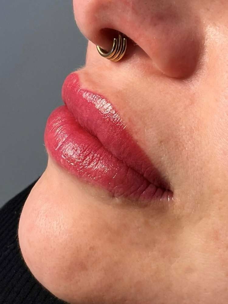 Un primer plano de los labios de una mujer con lápiz labial rojo y un anillo en la nariz.