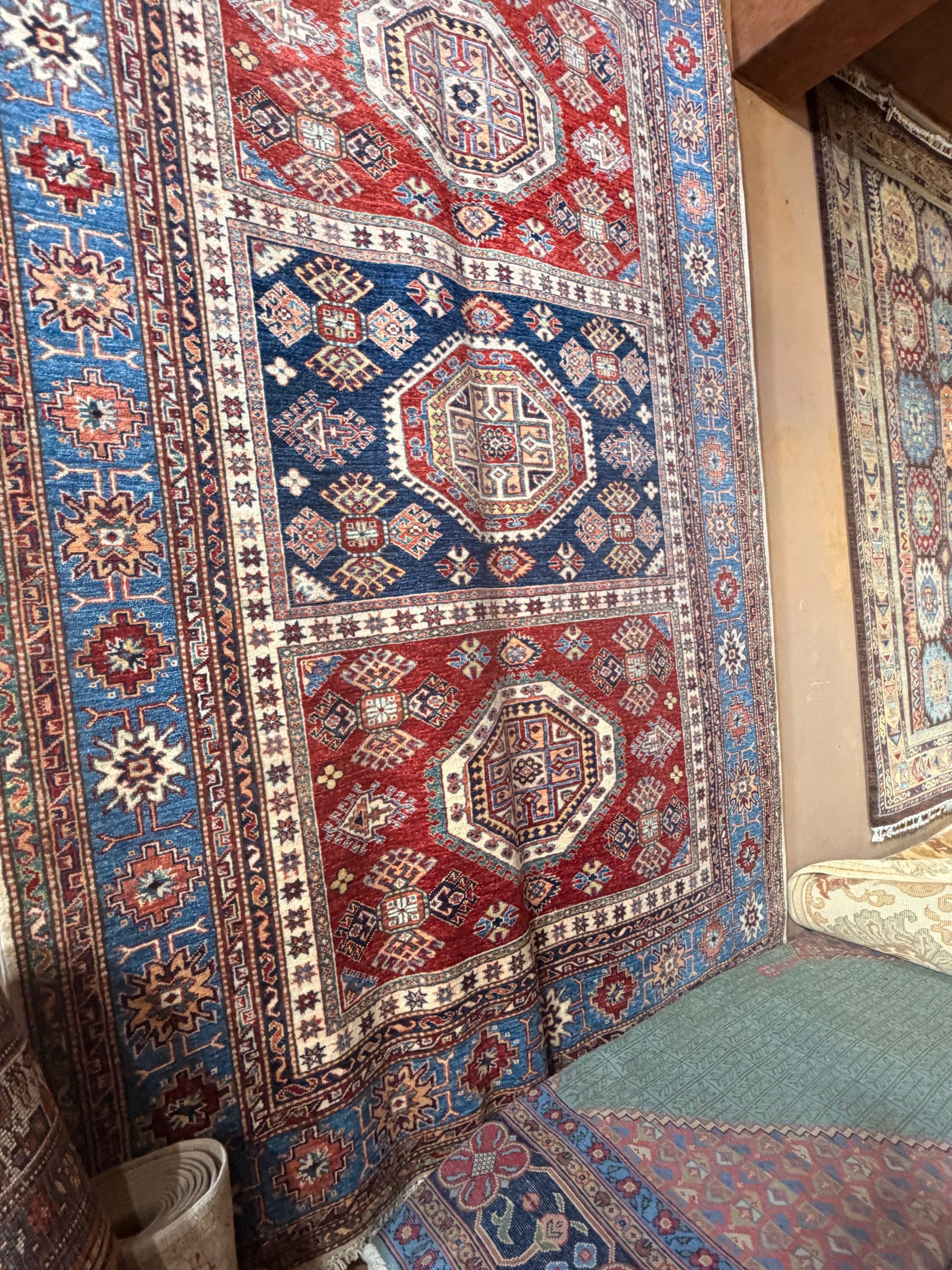 Tapis persans rouges et bleus à motifs suspendus dans un coin d’une boutique de tapis