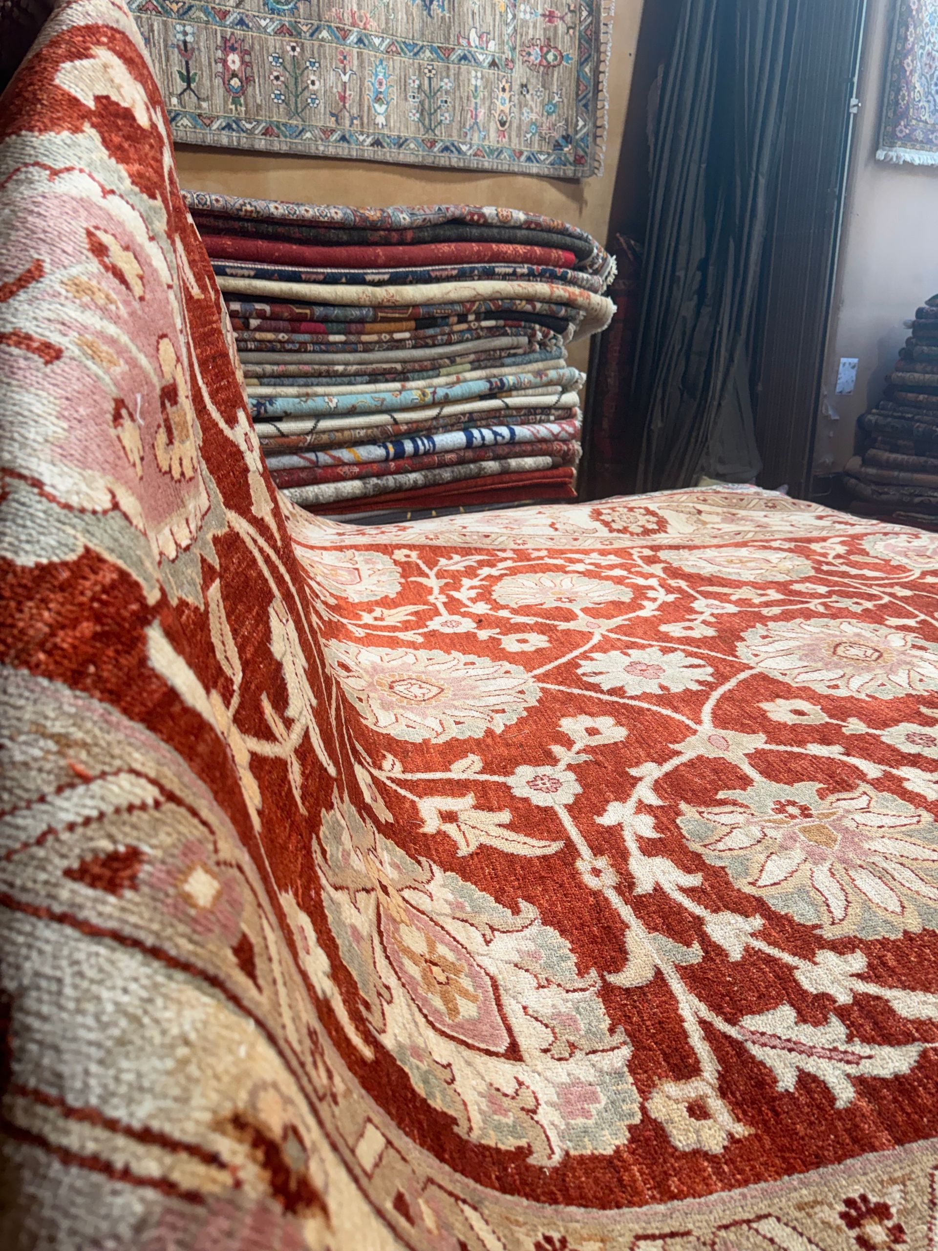 Canapé rouge à motifs, avec des tapis pliés empilés à l’arrière-plan