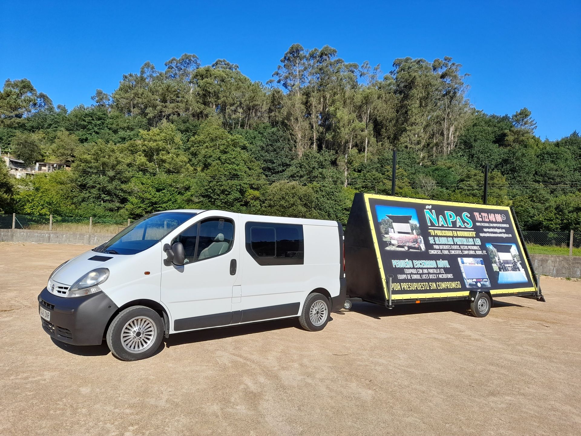 Una camioneta blanca con un remolque acoplado está estacionada en un campo.