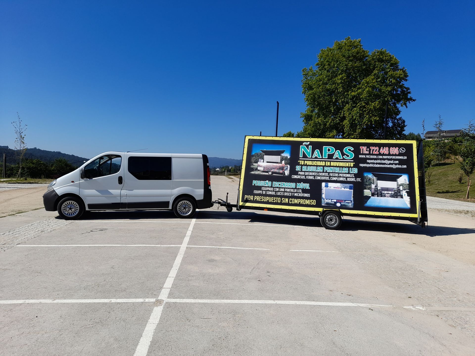 Una camioneta blanca con un remolque acoplado está estacionada en un estacionamiento.