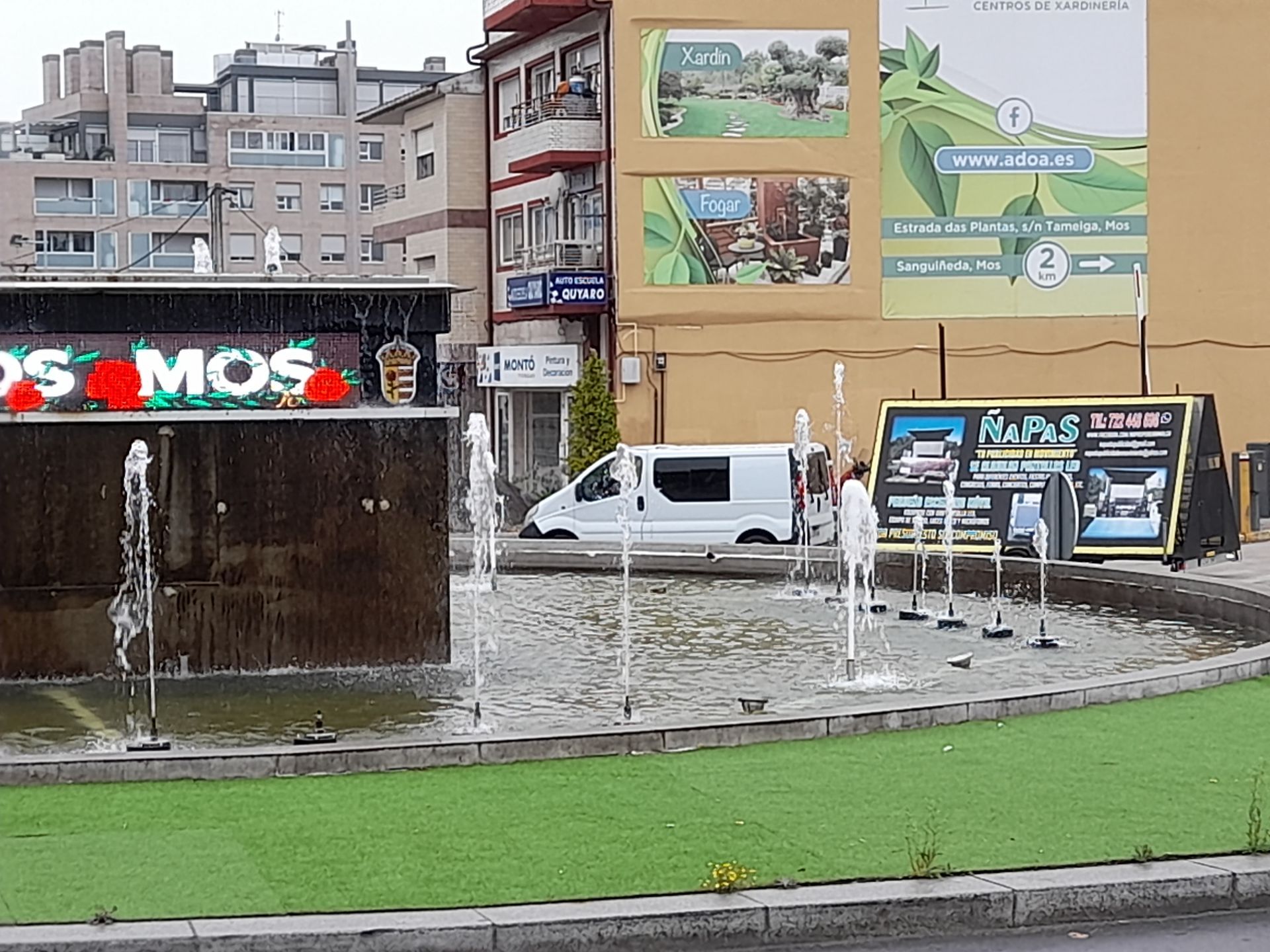 Una camioneta blanca está estacionada frente a un cartel que dice los mos