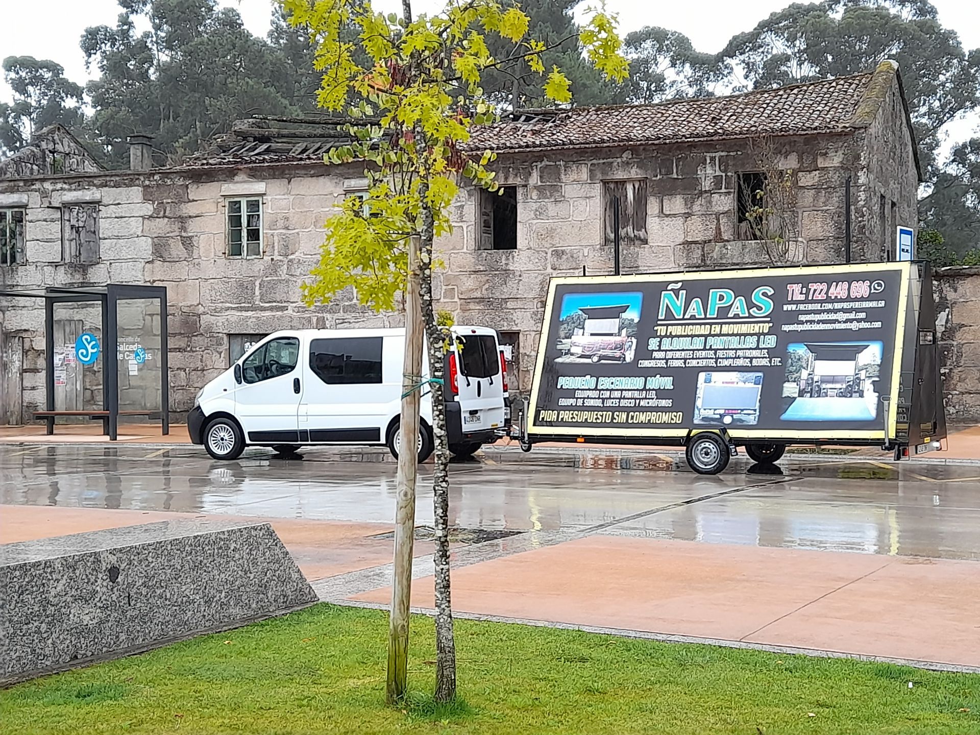 Una furgoneta blanca está estacionada delante de un edificio de piedra.