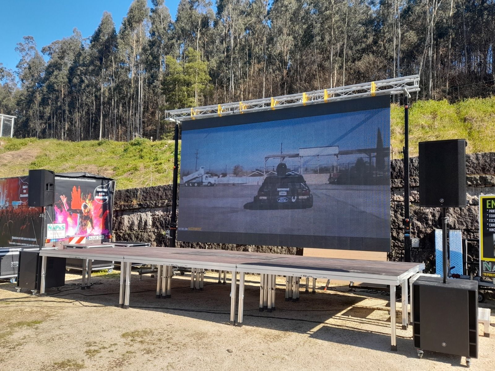 Una pantalla grande está en un escenario frente a un bosque.