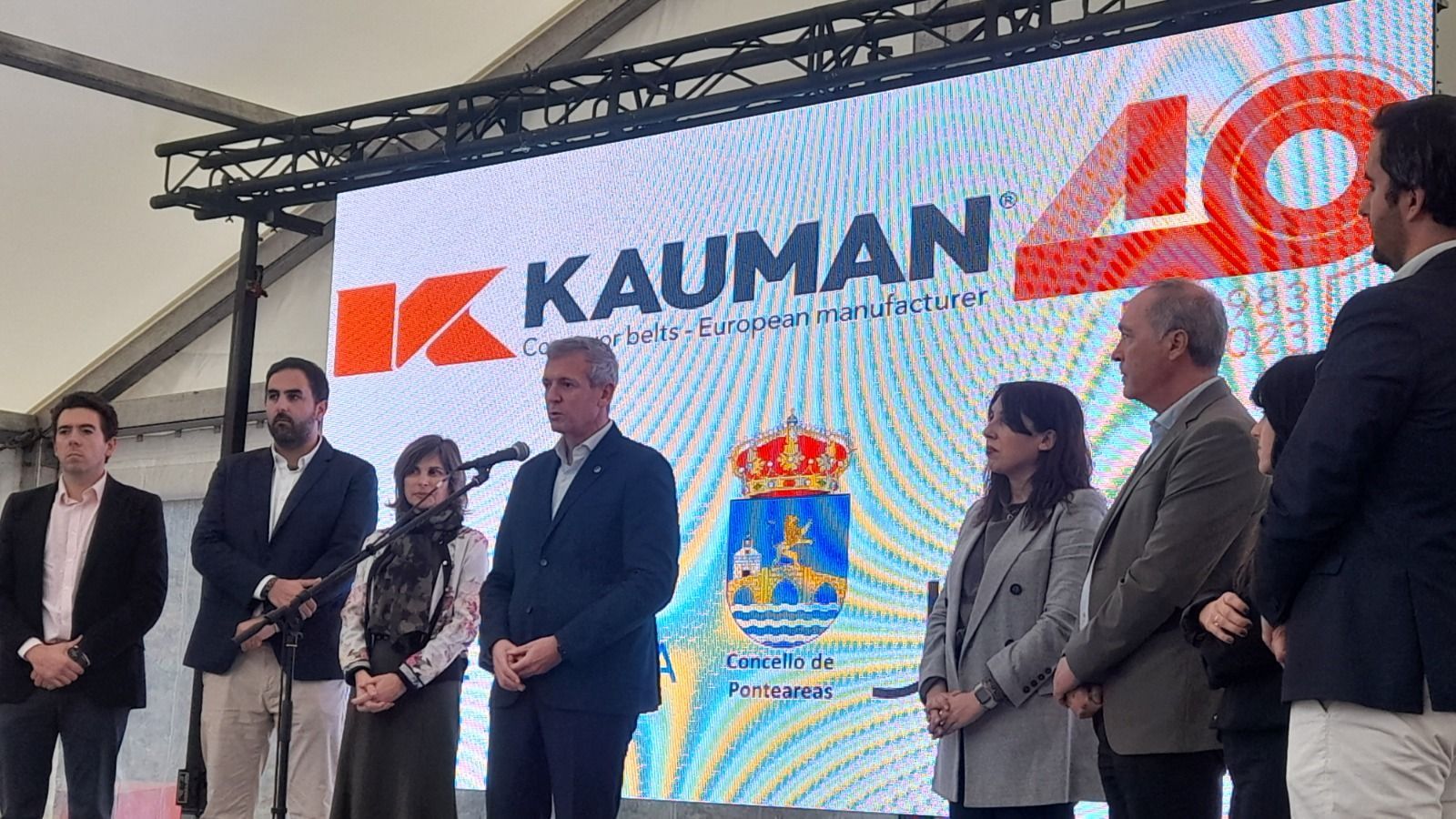 Un grupo de personas está de pie frente a una pantalla grande.