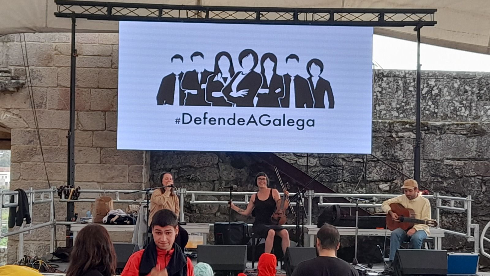 Un grupo de personas está de pie en un escenario frente a una pantalla grande.