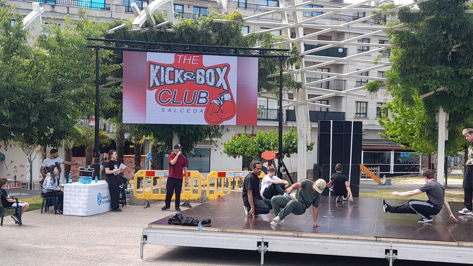 Un grupo de personas se presenta en un escenario frente a un cartel que dice kick box.
