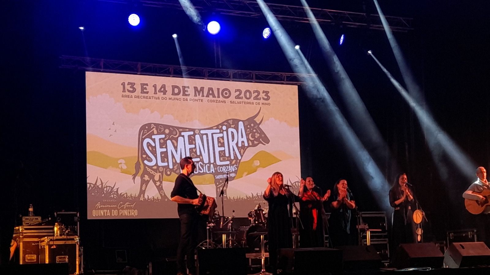 Un grupo de personas está de pie en un escenario frente a una pantalla grande.