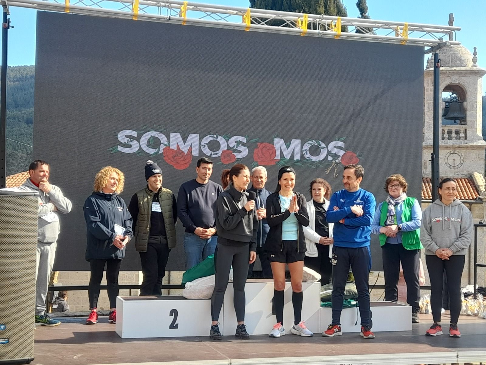 Un grupo de personas de pie frente a una pantalla grande que dice somos mos