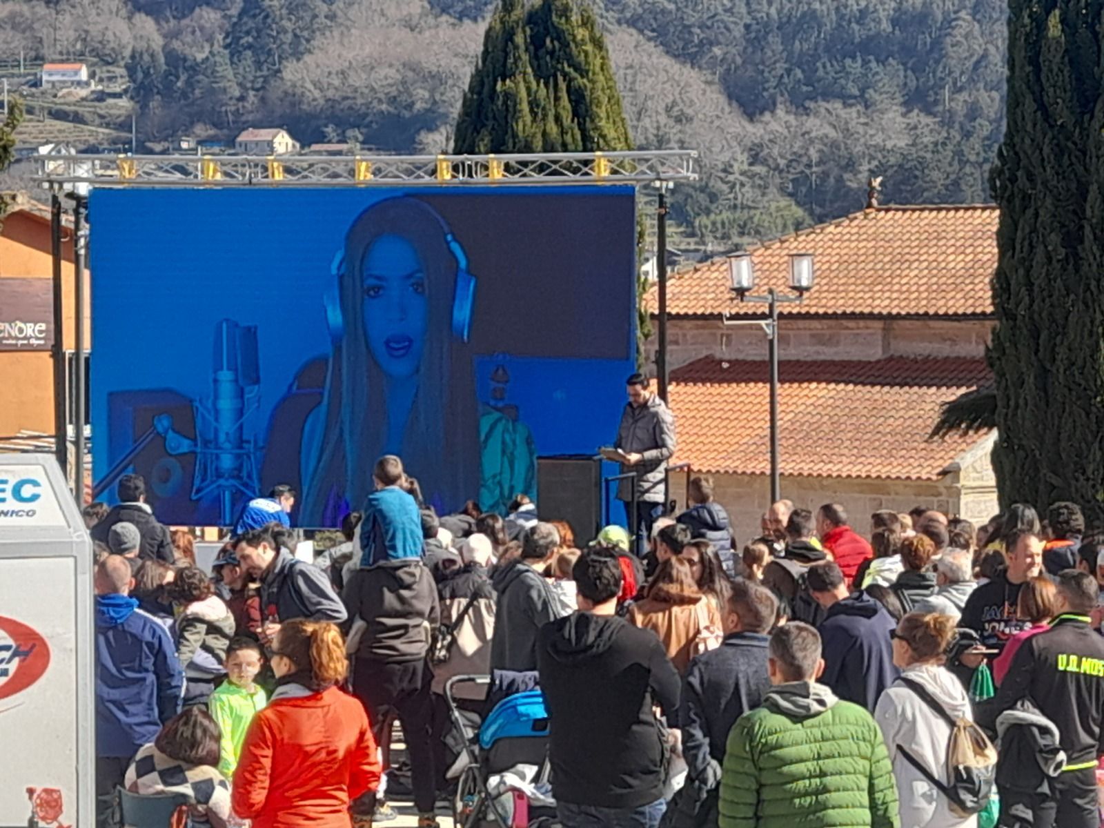 Un gran grupo de personas está de pie frente a una pantalla grande.