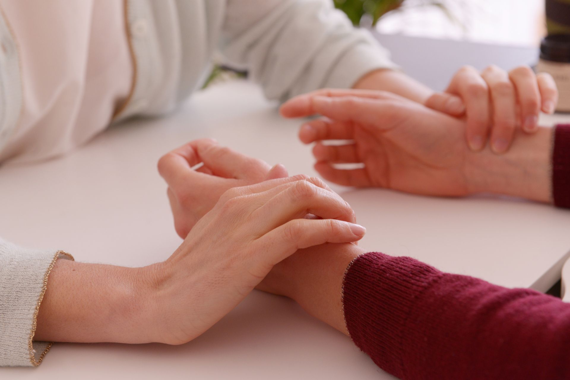 Les mains posées sur les poignets ; prise du pouls sur une table blanche.