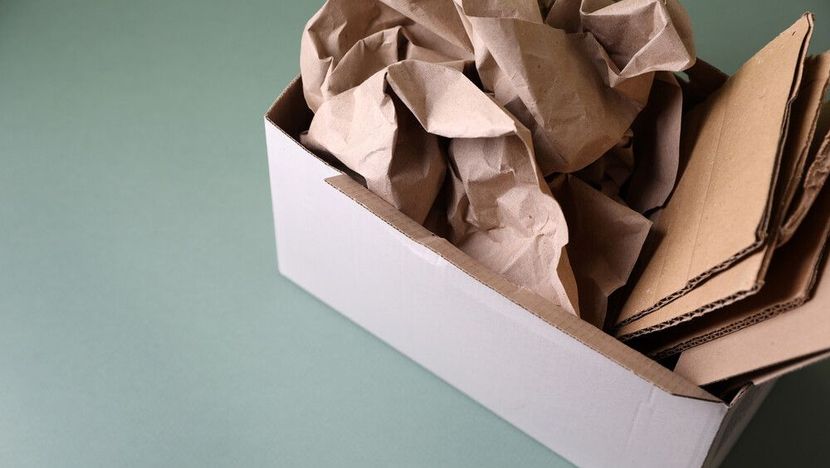Una caja blanca llena de cartón y papel marrón sobre una mesa.