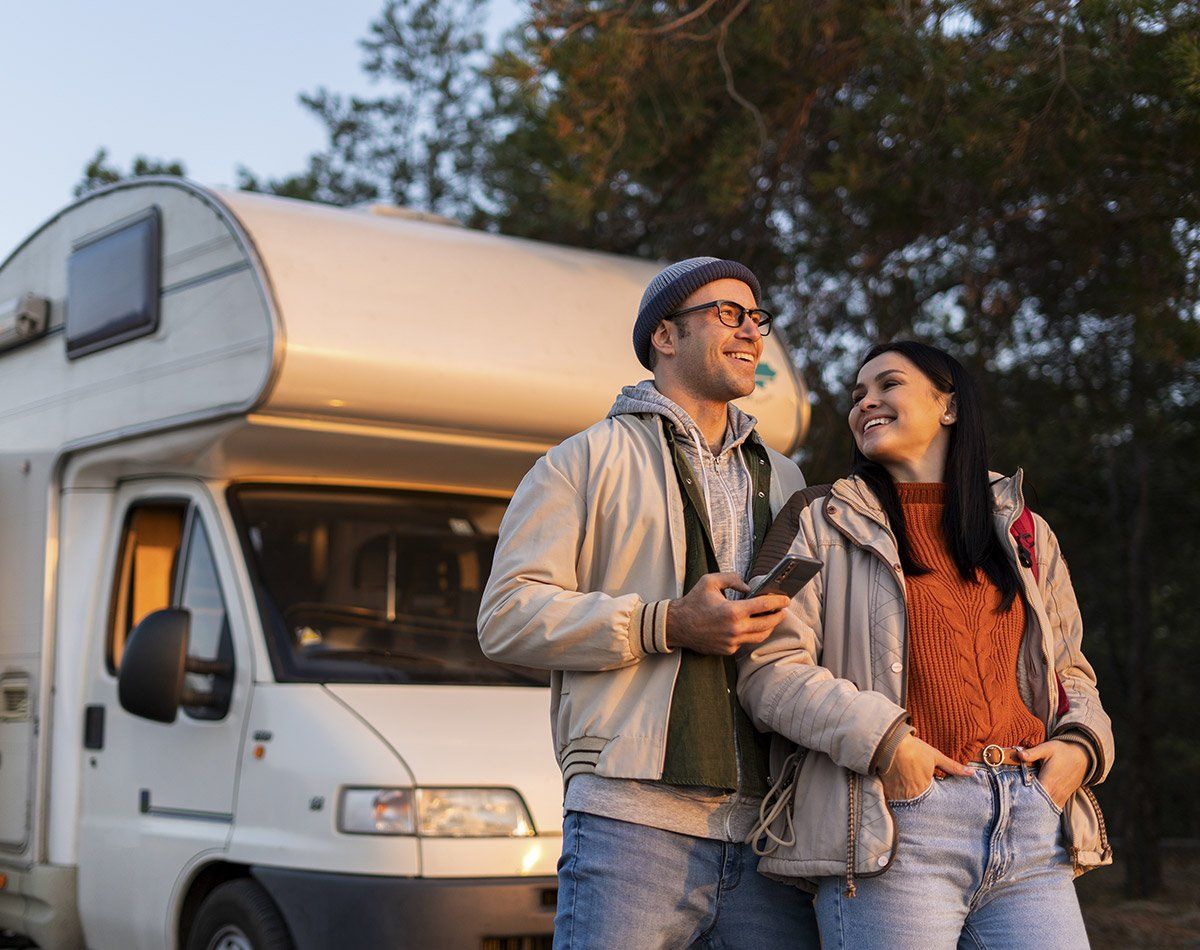 Couple de personnes souriantes debout devant un camping-car