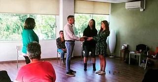 Personas en una habitación, una pareja recibe un documento de otras dos personas.