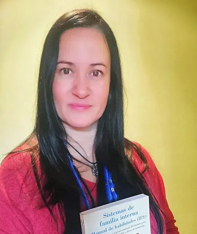 Mujer con cabello largo y oscuro, camisa roja, sosteniendo un libro titulado