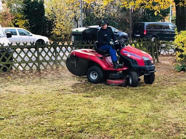Ein Mann fährt mit einem Rasenmäher über einen üppigen grünen Rasen.