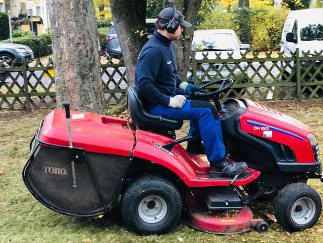 Ein Mann fährt in einem Garten mit einem Rasenmäher.