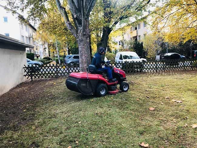 Ein Mann fährt in einem Garten mit einem Rasenmäher.