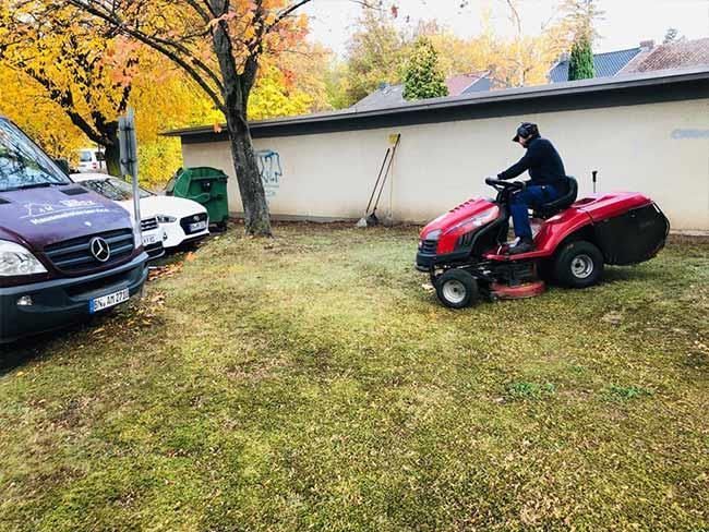 Ein Mann fährt in einem Garten mit einem Rasenmäher.