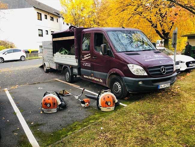 Ein Mercedes-Van steht auf einem Parkplatz neben einem Rasenmäher.
