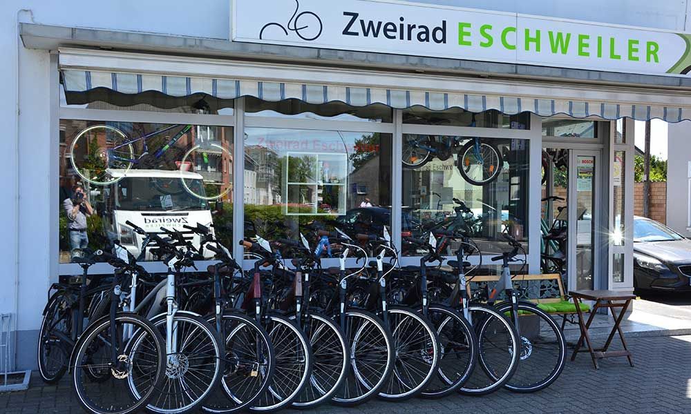 Eine Reihe von Fahrrädern parkt vor einem Geschäft namens Zweirad Eschweiler