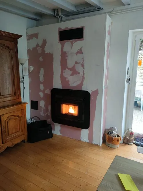 Poêle à granulés  mural dans un salon, installé pendant les travaux d'isolation.