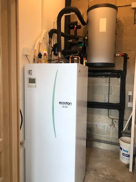 Chauffe-eau électrique blanc à cuve cylindrique, installé dans une buanderie.