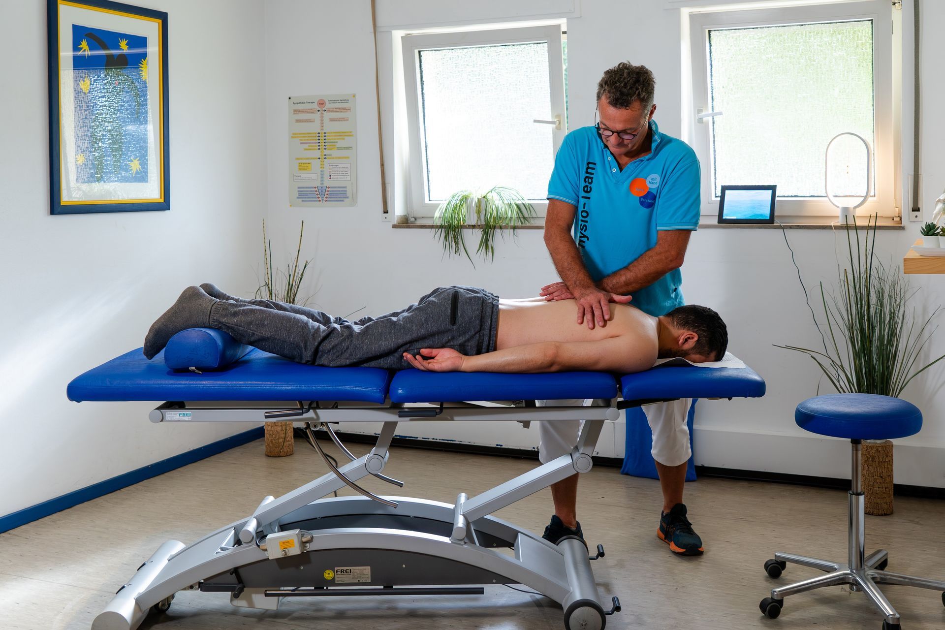 ein Mann liegt auf einem blauen Tisch und bekommt eine Massage