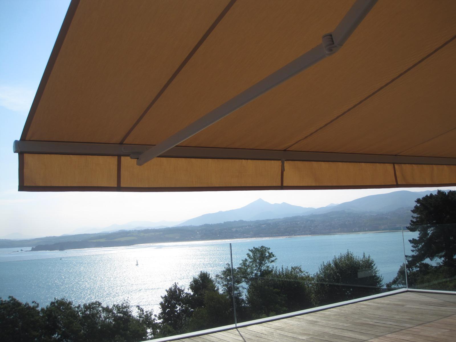 Store jaune donnant sur la mer et des arbres