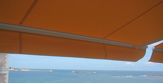 Dessous d'un store orange avec la mer en fond