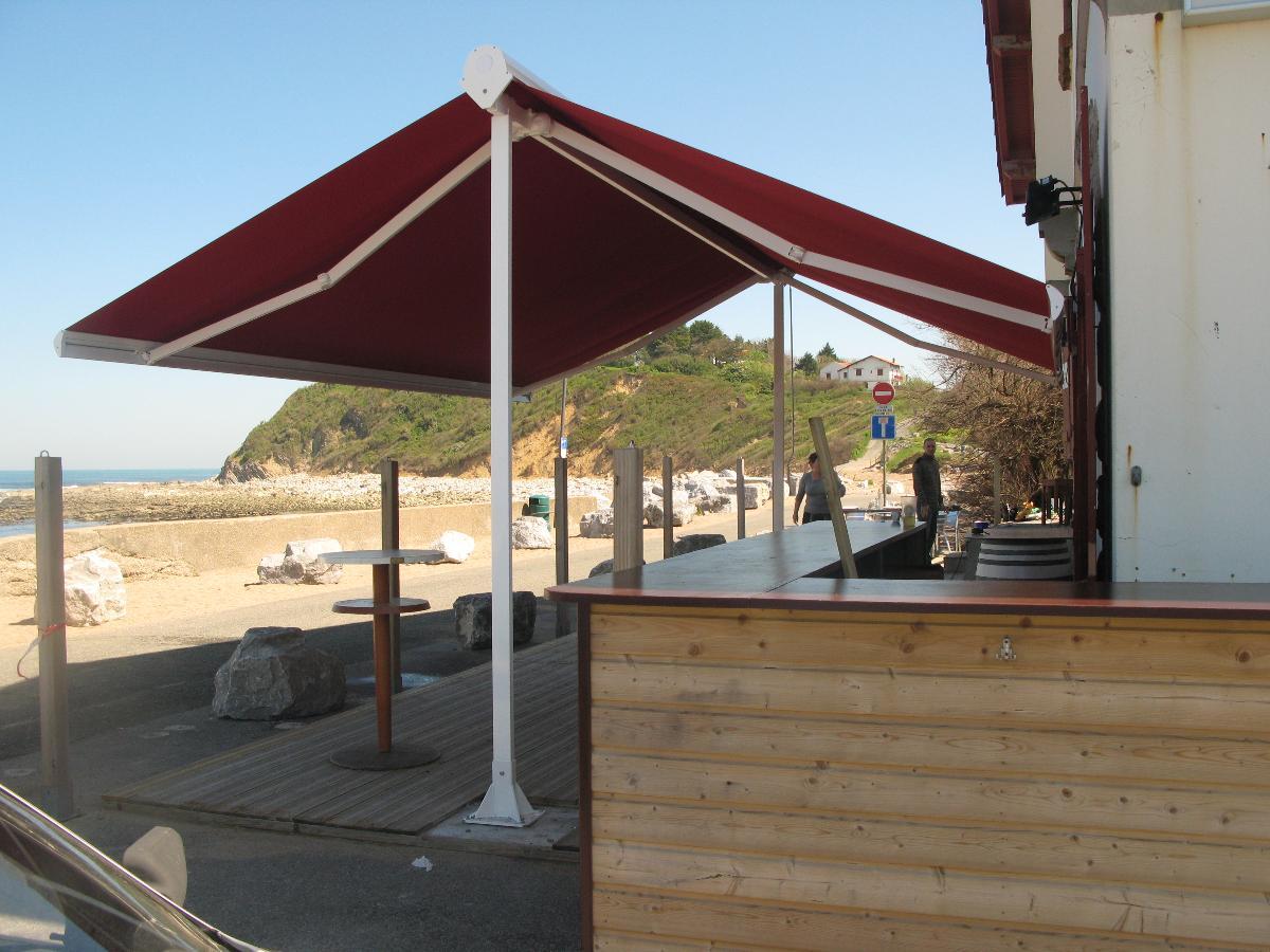 Store rouge sur pied donnant sur une terrasse et sur la plage