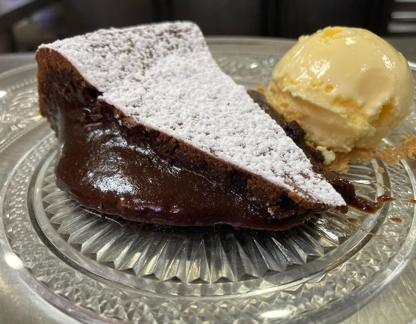 Una rebanada de pastel de chocolate con helado en un plato de vidrio.