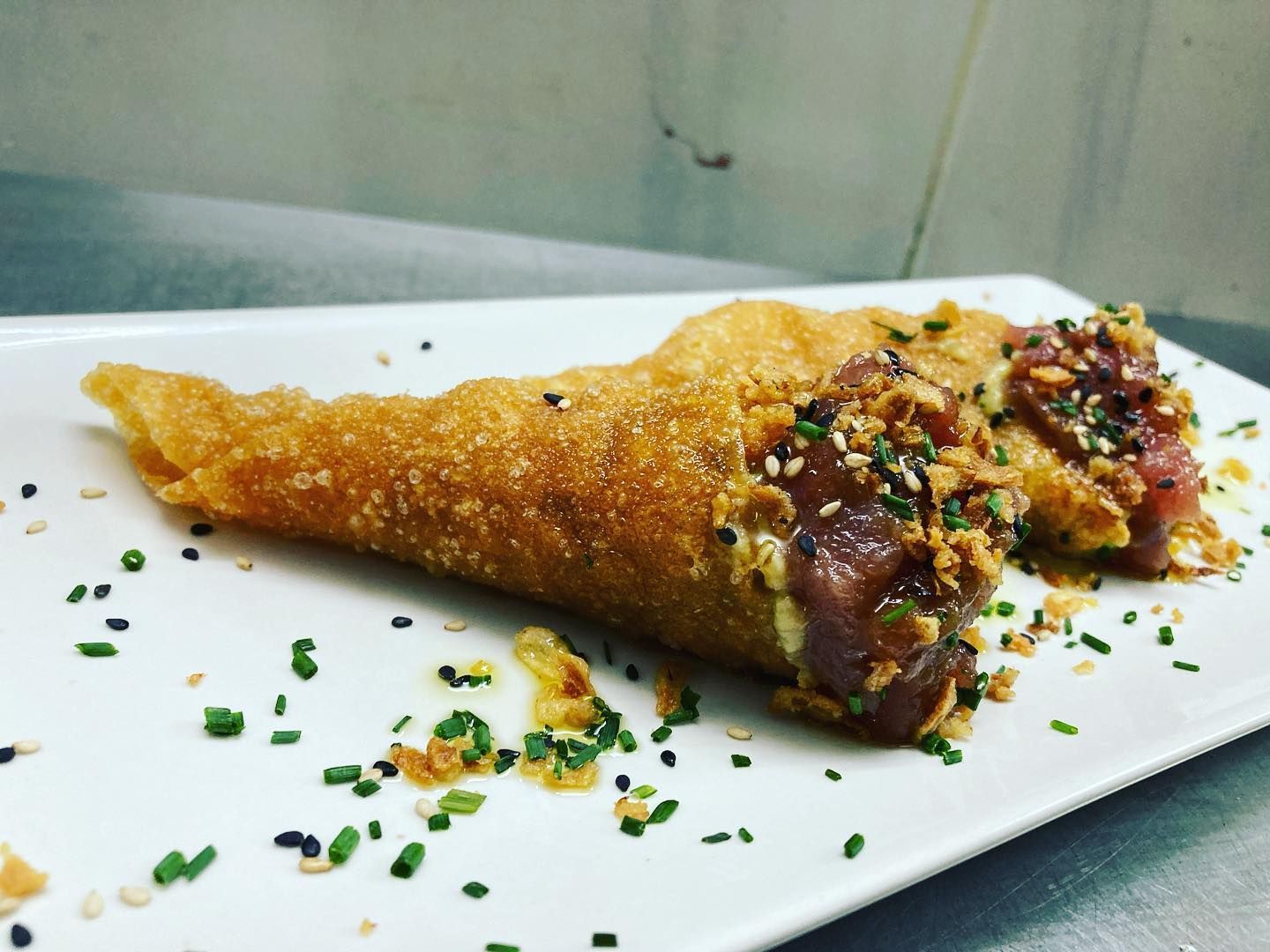 Un plato blanco cubierto con un cono frito relleno de carne y verduras.