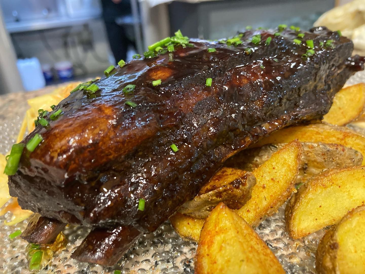 Un primer plano de un plato de comida con costillas y patatas sobre una mesa.