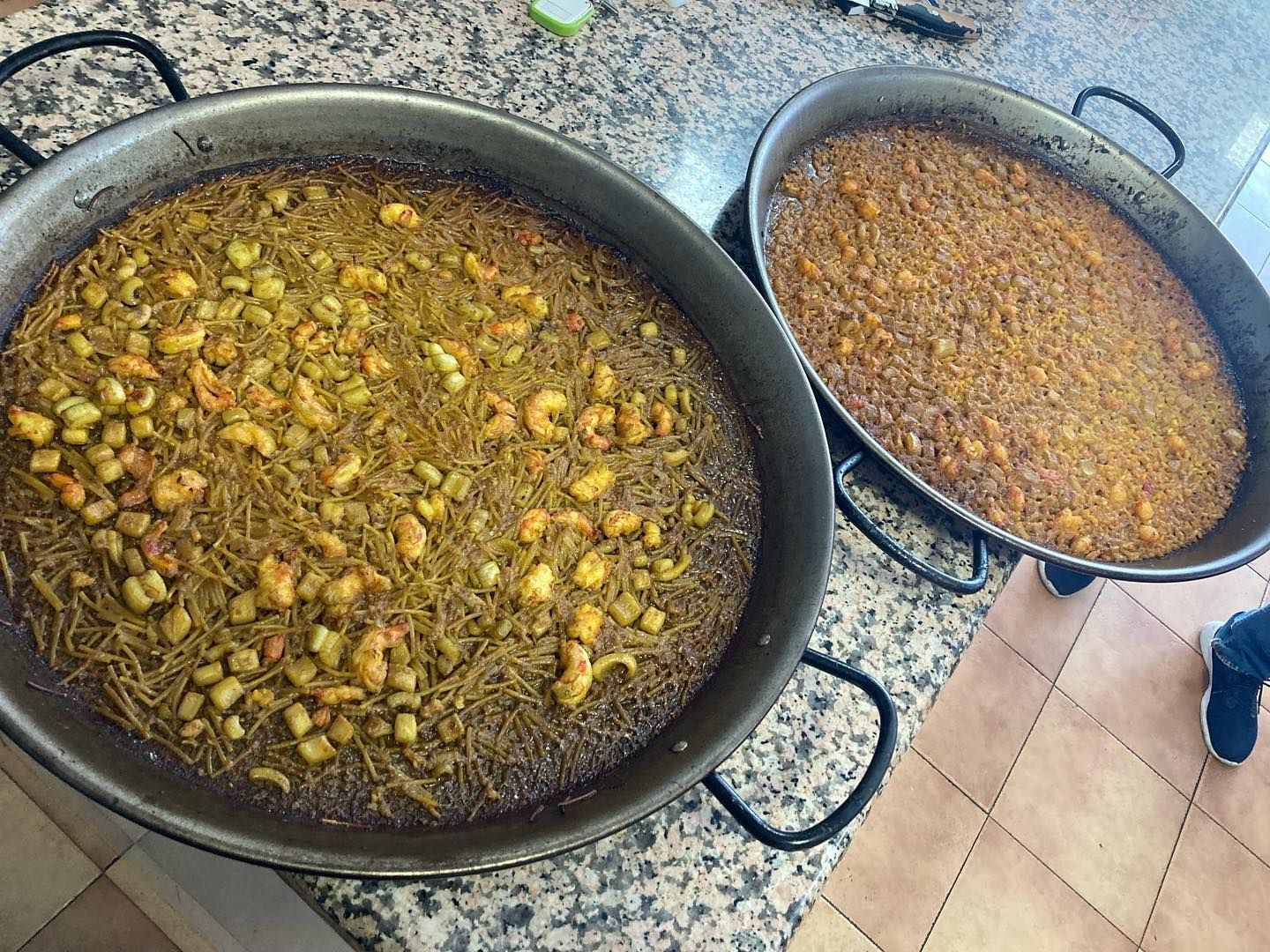 Hay dos cacerolas con comida sobre un mostrador.