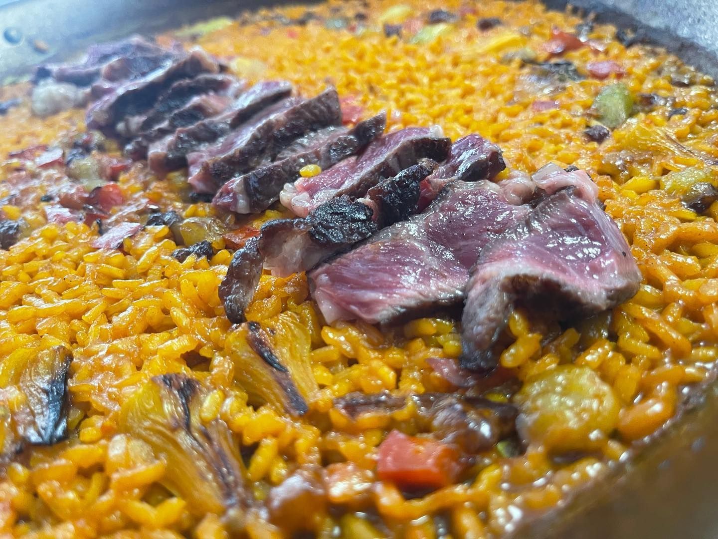 Un primer plano de una sartén de arroz con carne y verduras.