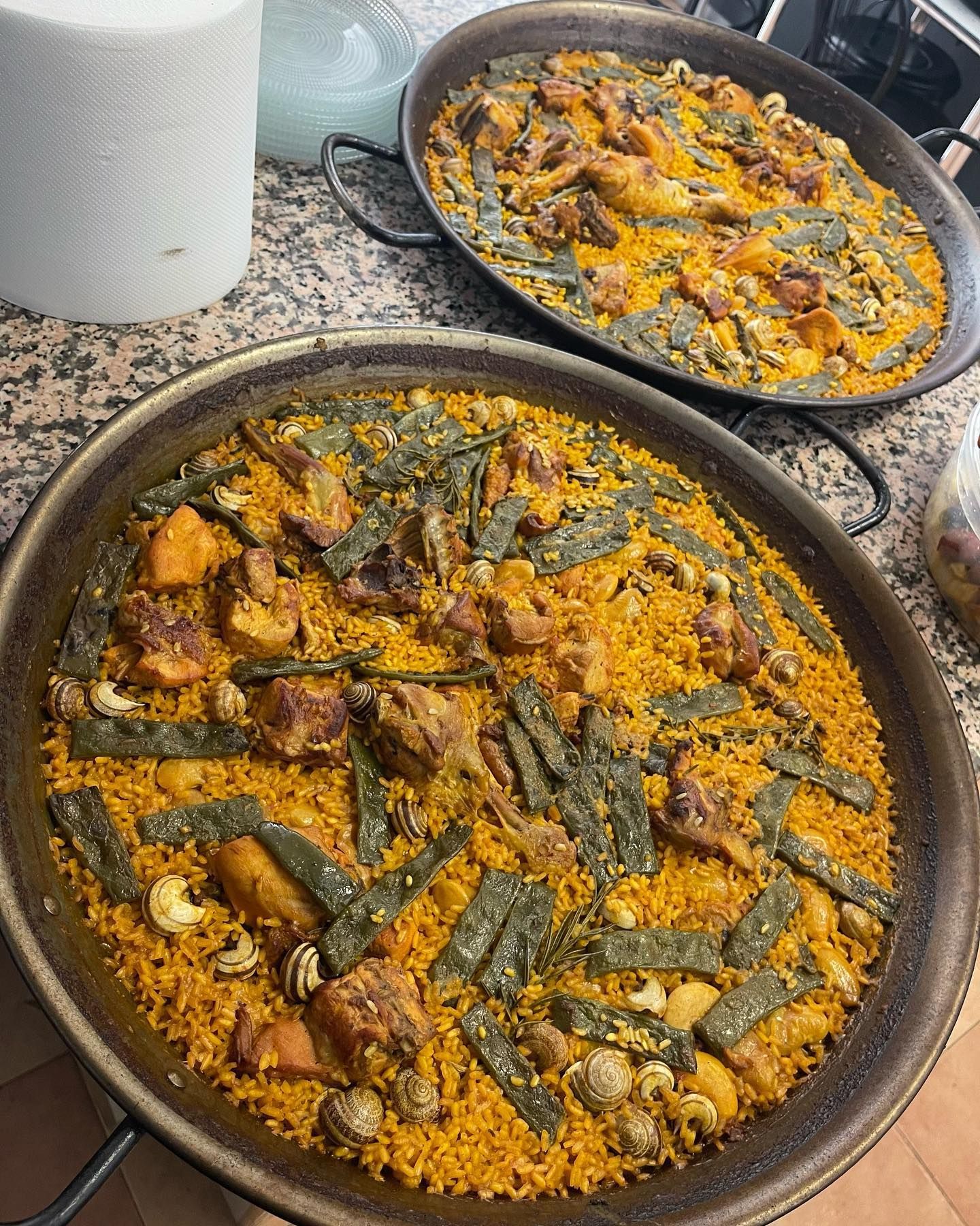 Hay dos sartenes de paella sobre una encimera.