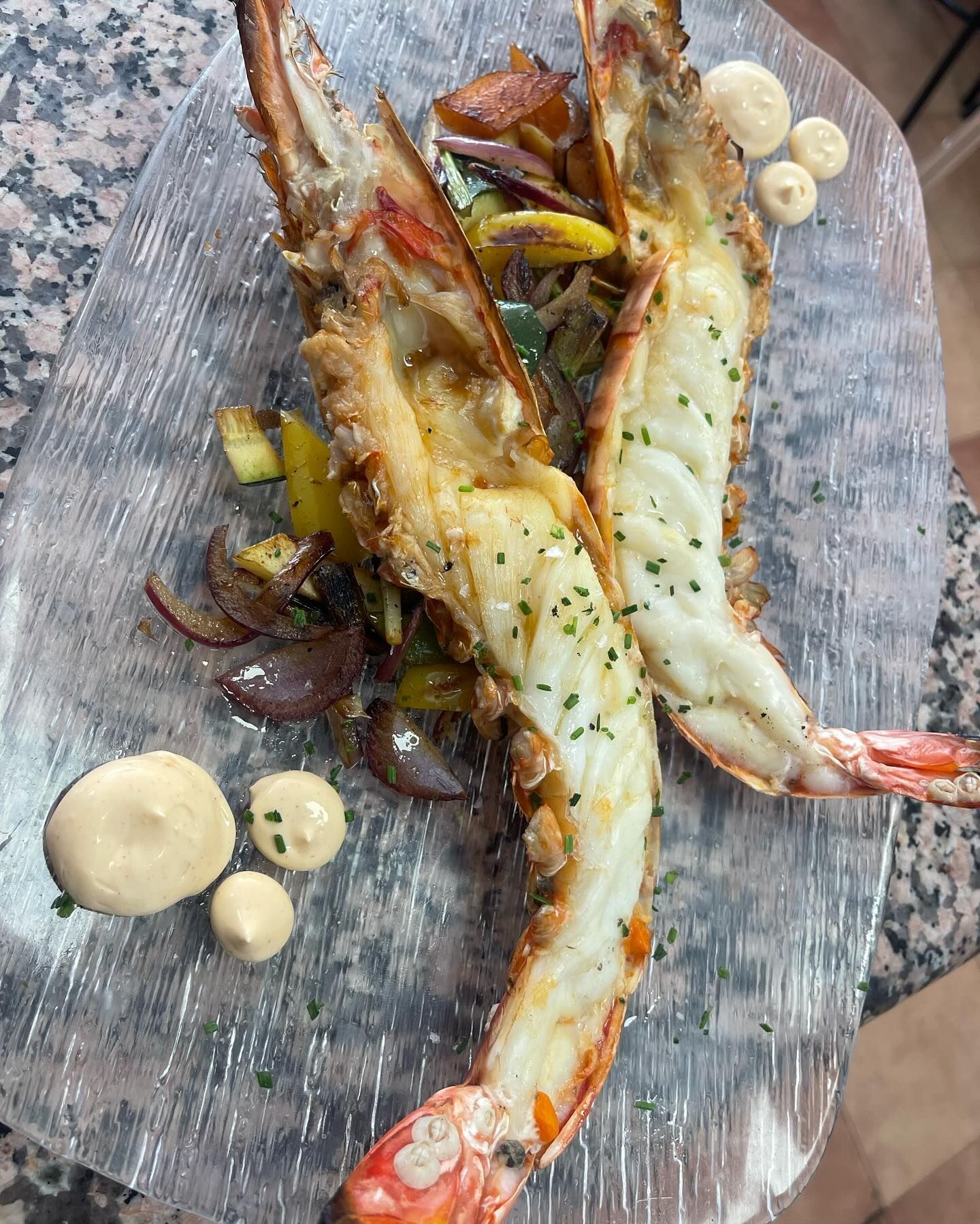 Un plato de comida con camarones y verduras en una mesa.