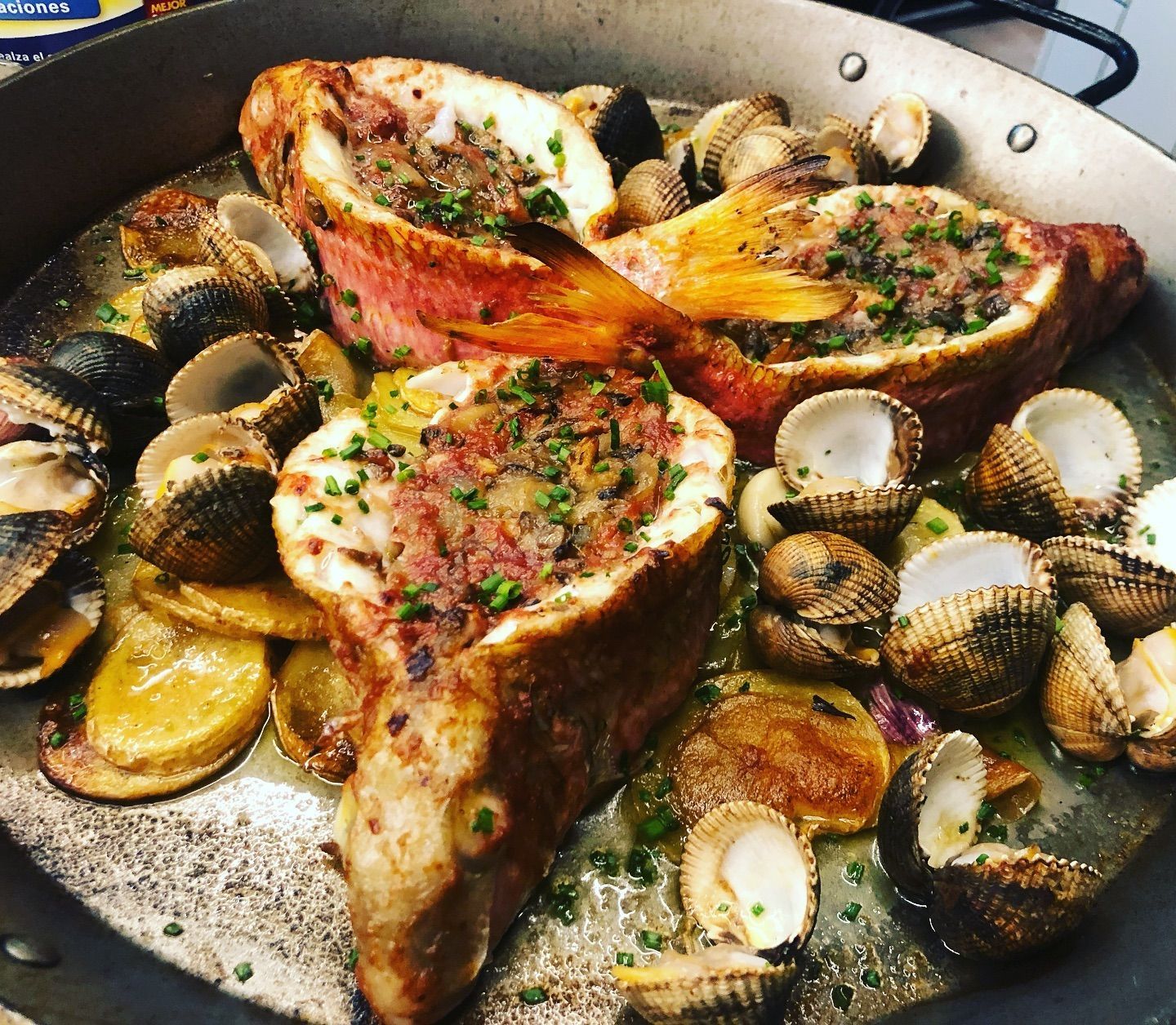 Una sartén llena de comida que incluía carne y almejas.