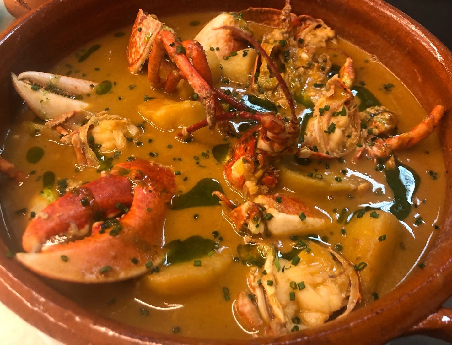 Un tazón de sopa con langostas y camarones.