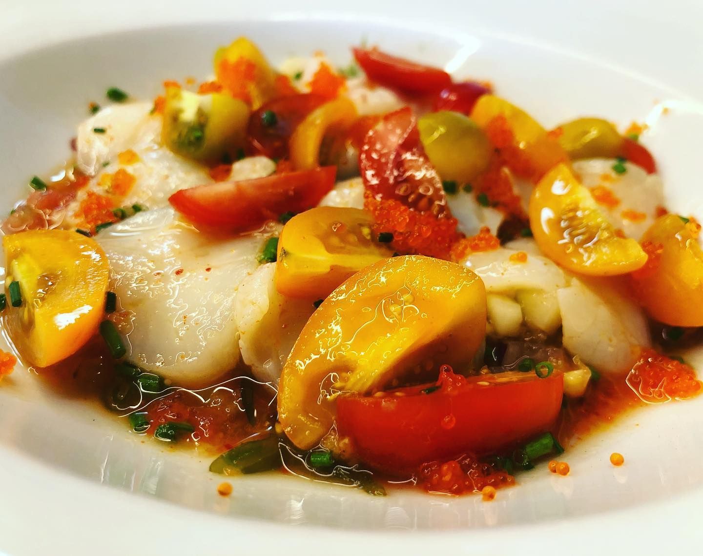 Un primer plano de un plato de comida con tomates y otras verduras.