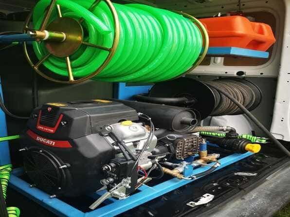 Una máquina con una manguera verde conectada a ella está en la parte trasera de una camioneta.