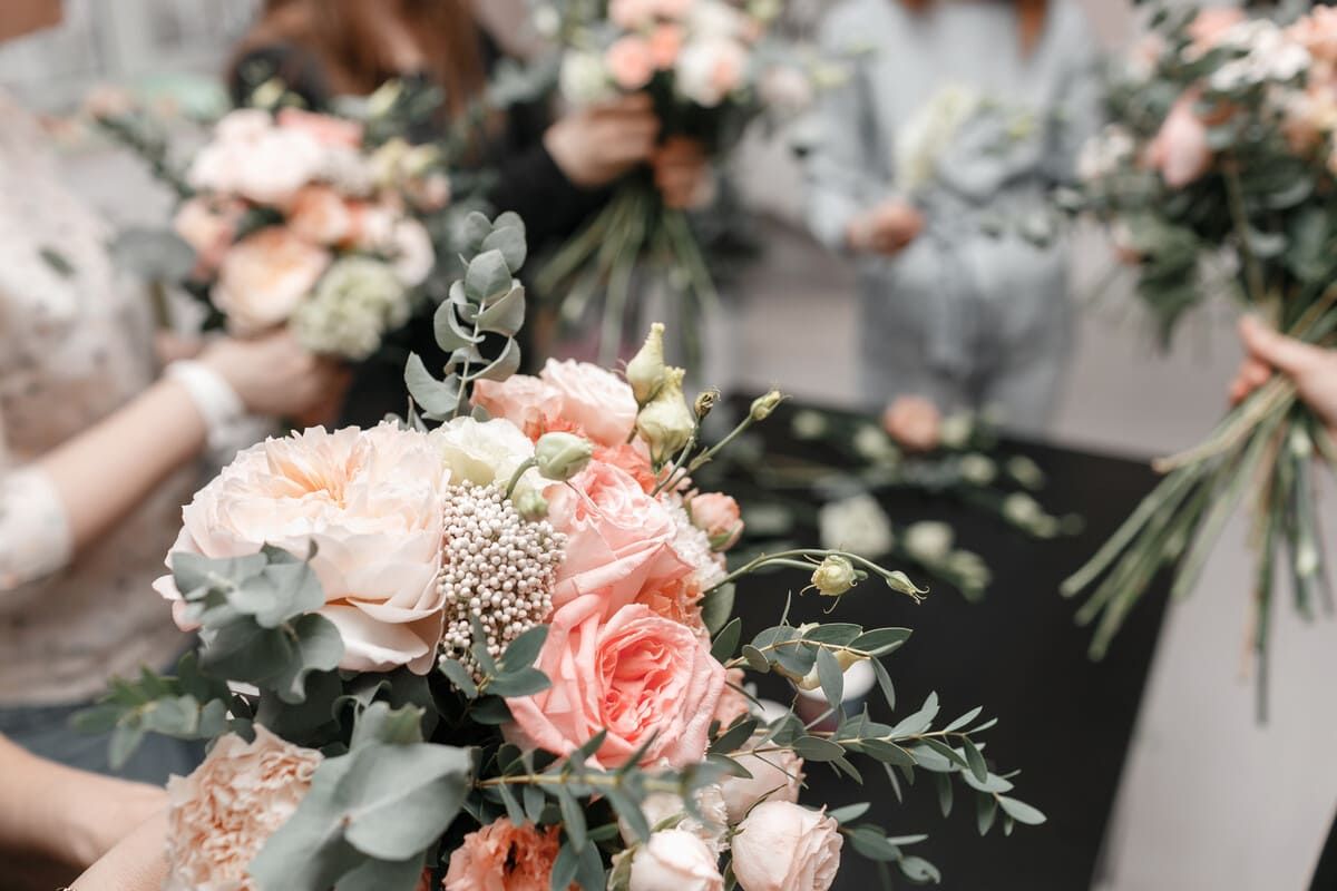 Un grupo de mujeres sostienen ramos de flores en sus manos.