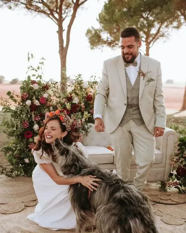 Una novia y un novio acariciando a un perro en su boda.