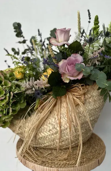 Una cesta llena de flores está sobre una mesa de madera.