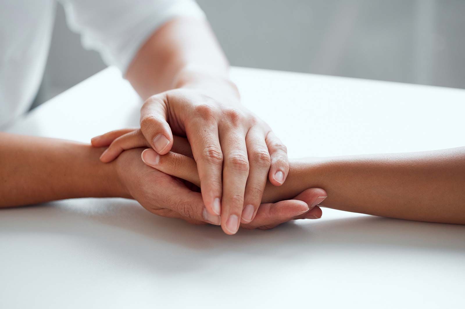 Una persona sostiene la mano de otra persona sobre una mesa.