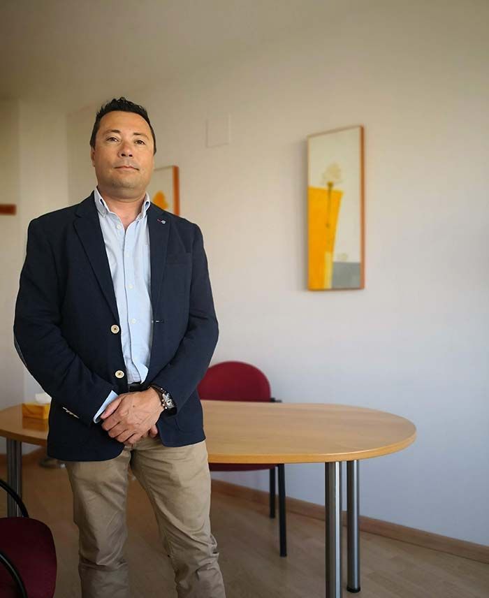 Un hombre con traje está de pie frente a una mesa.