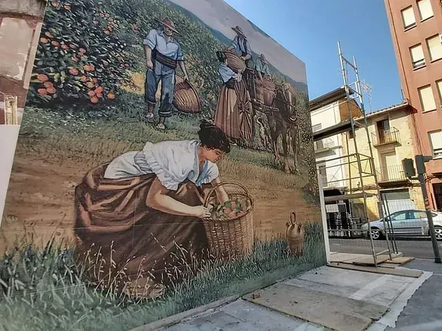 Un gran mural de una mujer recogiendo flores en una pared.