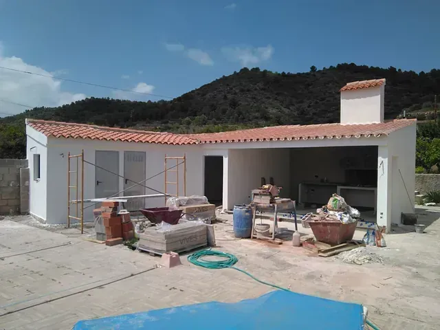 Una casa blanca con techo de tejas rojas está en construcción